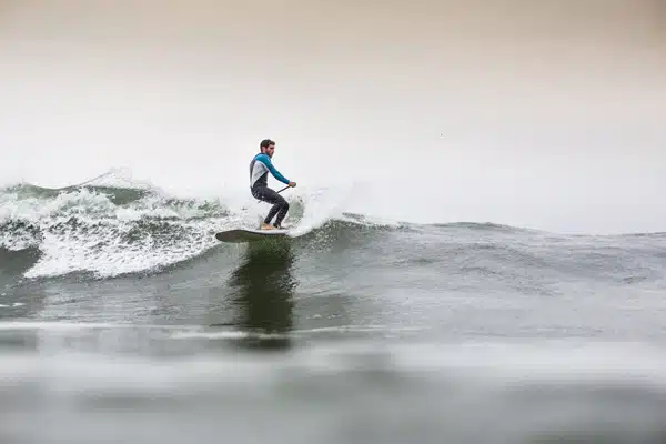 SUP Surfer catching a wave in Ericeira, Portugal with Mauka Lodge